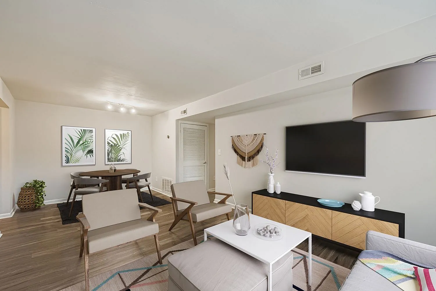 Living room with wood-style plank flooring, mid-century chairs, flat-screen TV, black media console
