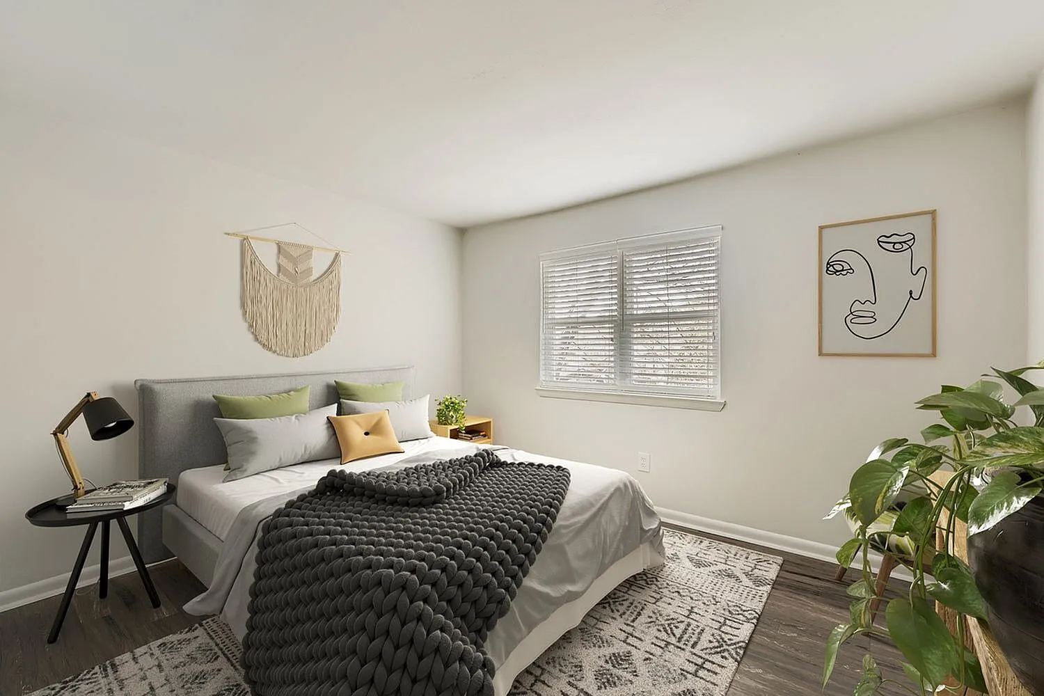 Primary bedroom, gray upholstered headboard, black quilted bedding, wood-style plank flooring, plants