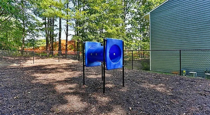 Community amenity area, blue tunnel tube structure, mulch ground cover, tree canopy, green siding building