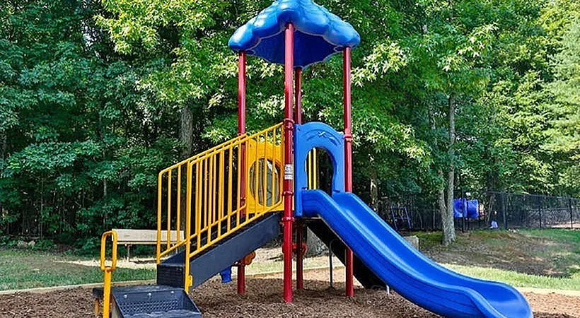 Playground, blue slide, red support posts, yellow railings, blue canopy
