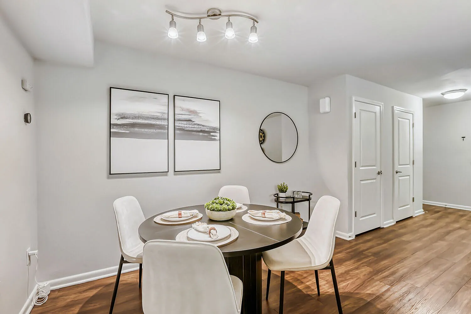 Dining room, round wood table, upholstered white chairs, wood-style plank flooring