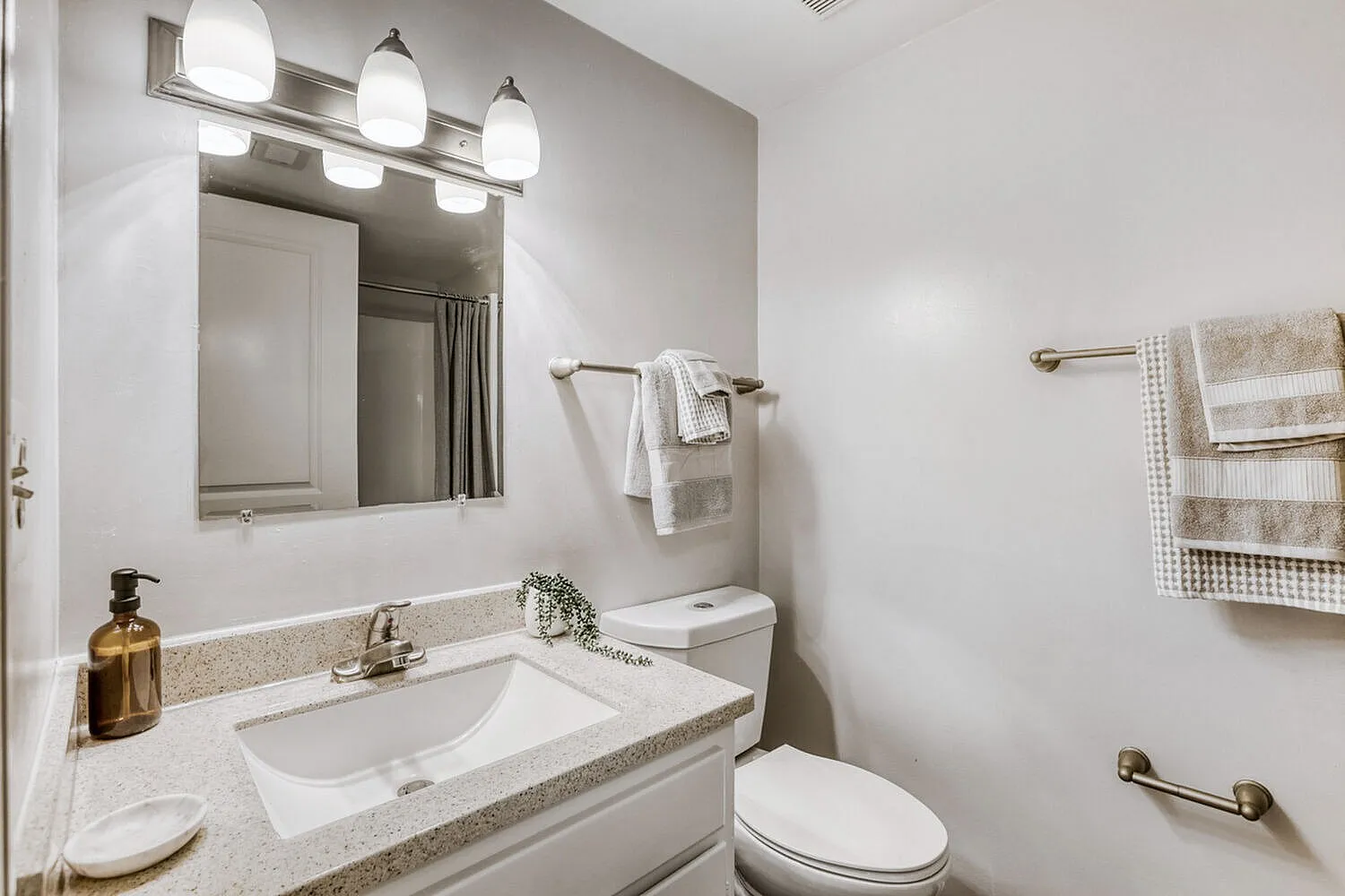 Bathroom, quartz countertop, white integrated sink, mirror with vanity lights, toilet