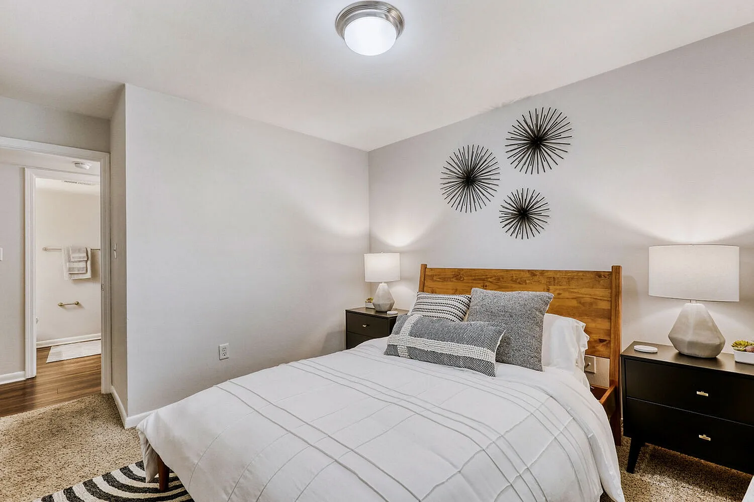 Primary bedroom, wood-style plank flooring, wood bed frame, pendant lighting fixtures