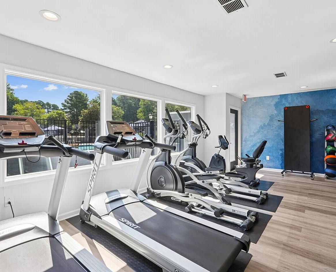 Fitness center, treadmills, elliptical machines, wood-style plank flooring, blue accent wall