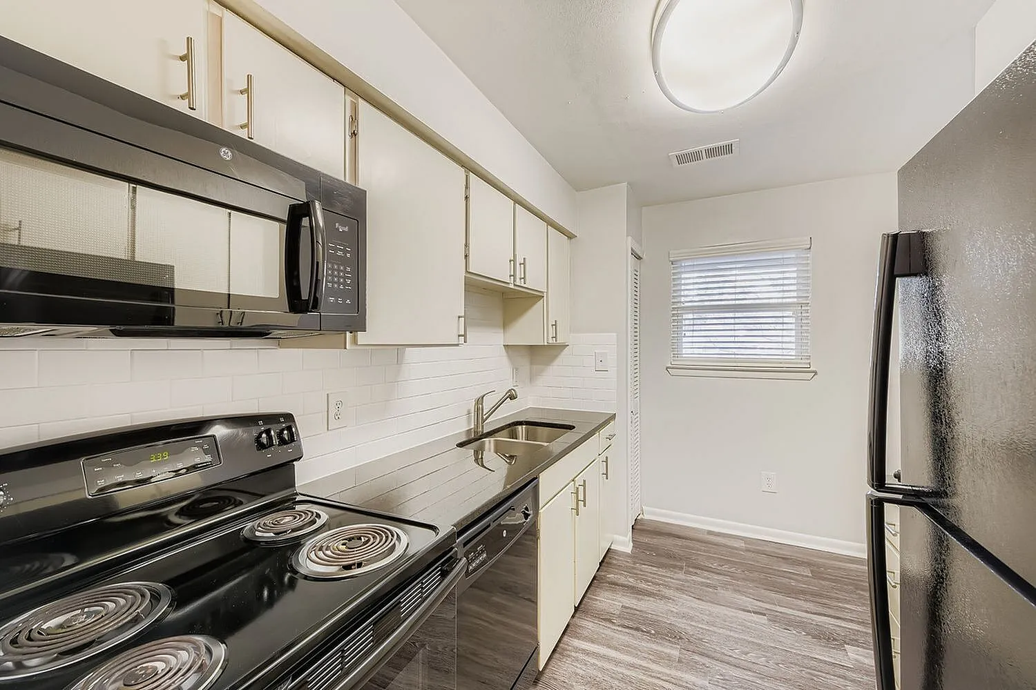 Kitchen, white shaker cabinetry, quartz countertops, black stainless appliances, wood-style plank flooring