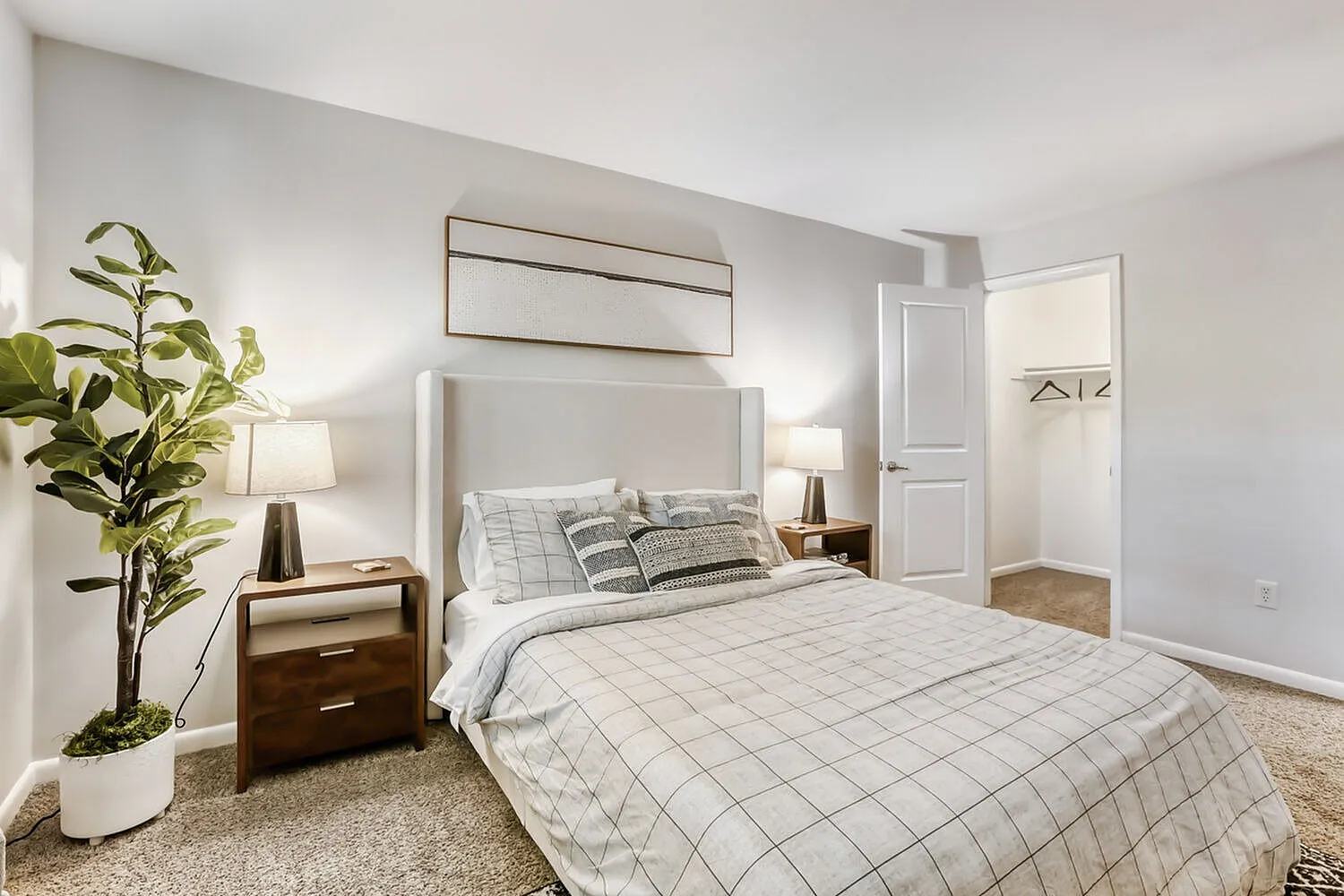 Primary bedroom, wood-style plank flooring, upholstered headboard, potted plant accent
