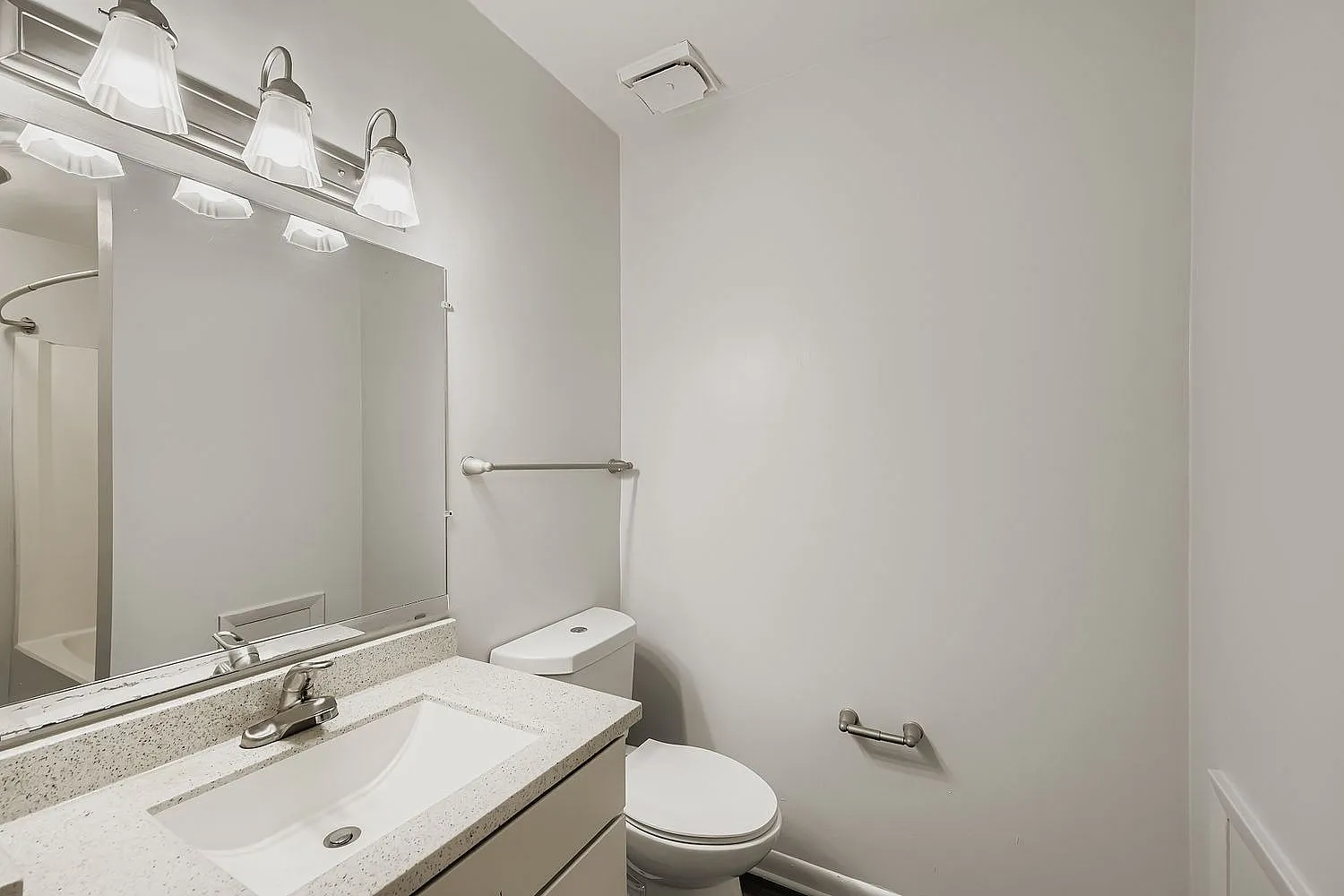 Bathroom, gray vanity with quartz countertop, large mirror with lighting, white toilet