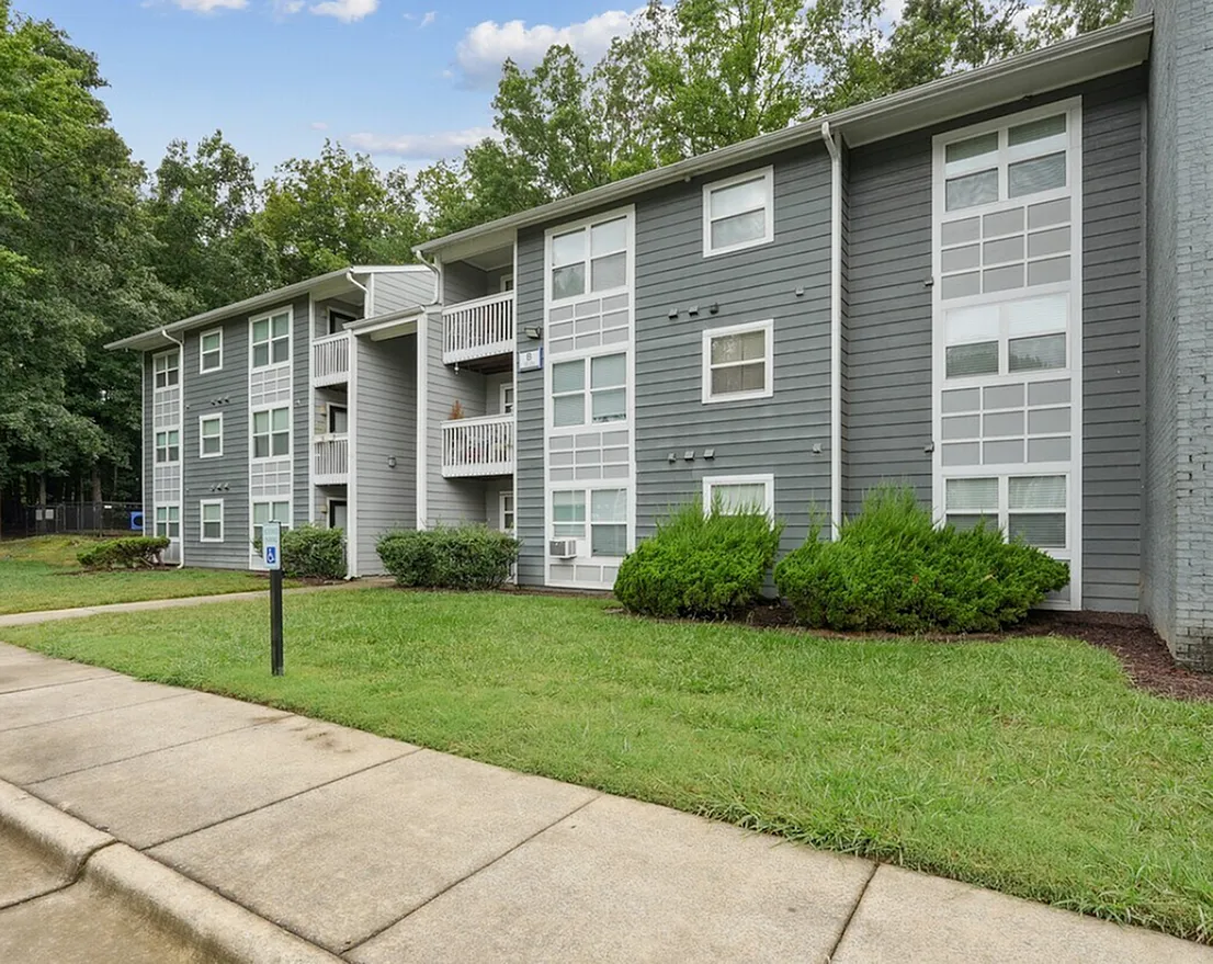 Multi-story apartment building, gray fiber cement siding, white-trimmed windows, tiered balconies, landscaping
