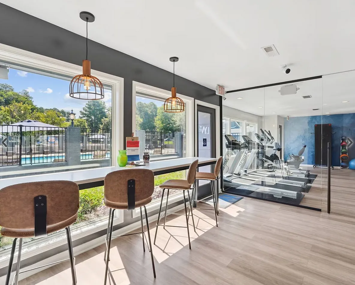 Fitness center, wood-style plank flooring, high windows, leather chairs, pendant lighting, glass partition