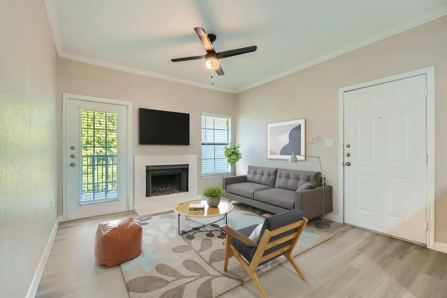 Living room with wood-style plank flooring, gray sofa, fireplace with TV, ceiling fan