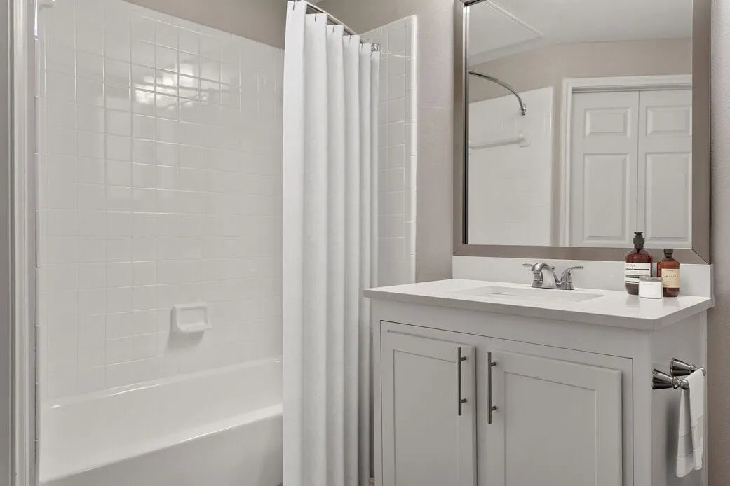 Bathroom, white vanity cabinetry, quartz countertop, framed mirror, gray shower enclosure