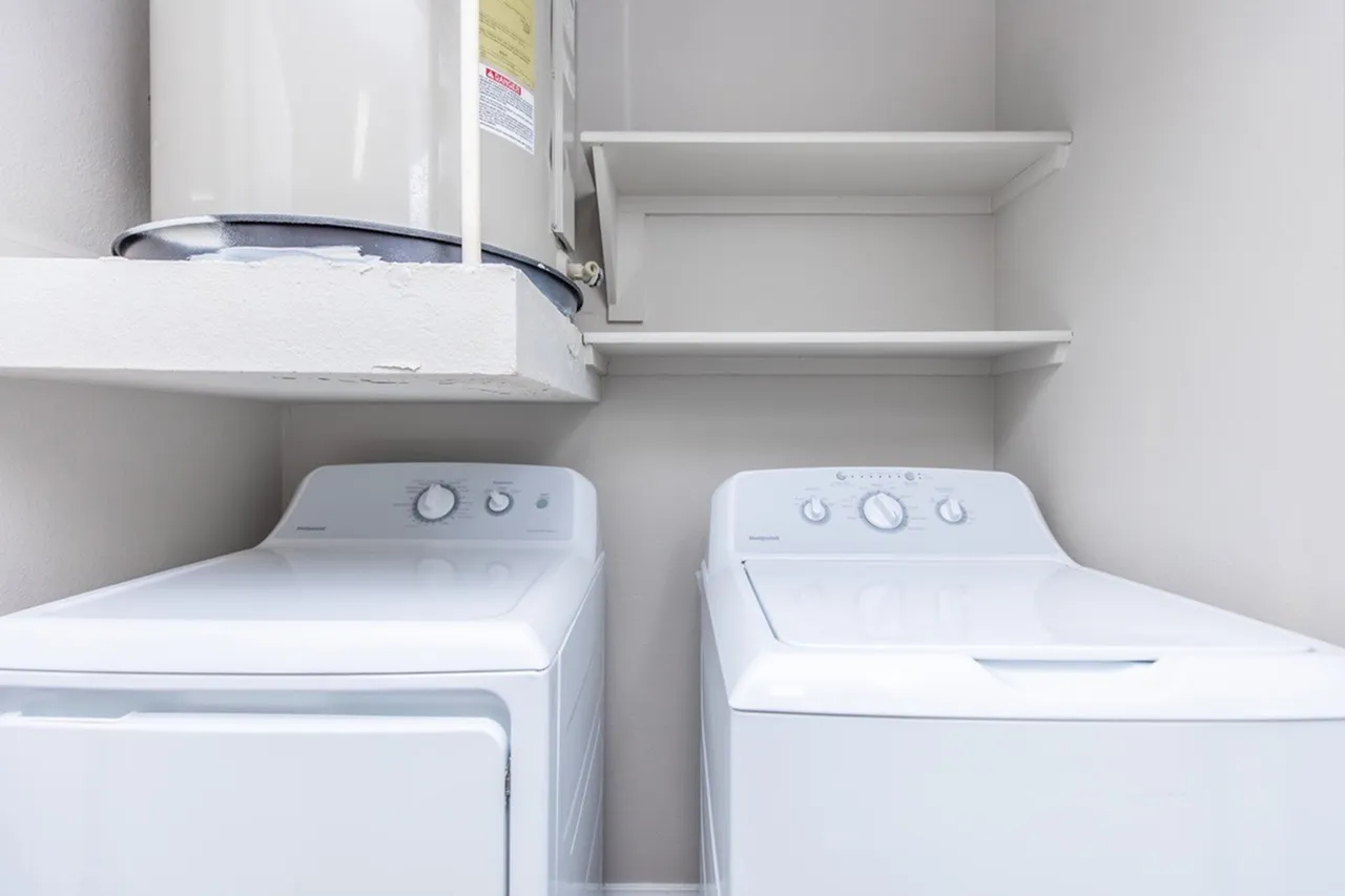 Laundry room, white washer and dryer, white shelving, water heater