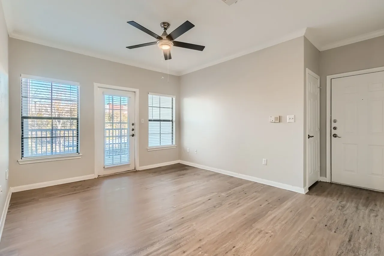 Living room, wood-style plank flooring, ceiling fan, glass doors, window with shutters