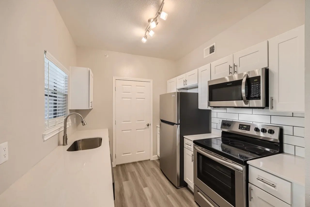 Kitchen, white shaker cabinetry, quartz countertops, stainless steel appliances, wood-style plank flooring