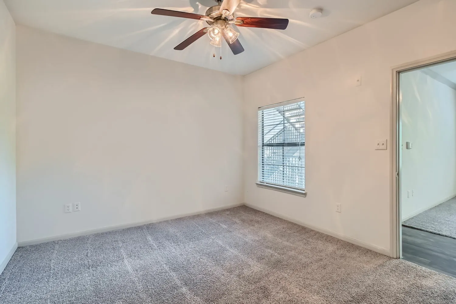 Bedroom, gray carpet flooring, ceiling fan with light fixture, window with blinds