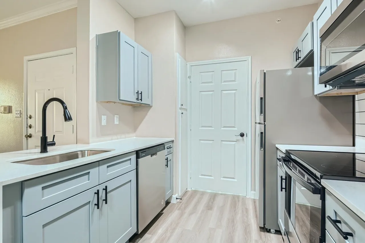 Kitchen, light blue shaker cabinetry, quartz countertops, stainless appliances, wood-style plank flooring