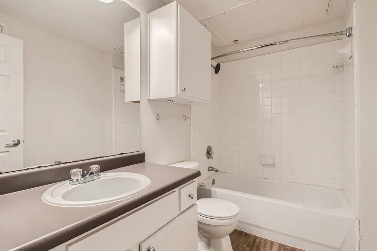 Bathroom, oval sink vanity, dark countertop, white medicine cabinet, toilet, bathtub with shower