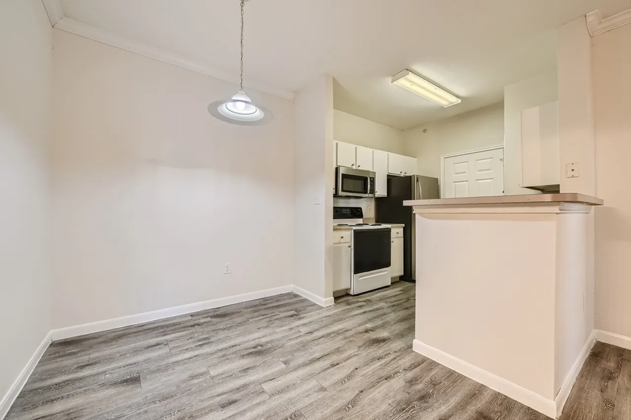 Kitchen, white shaker cabinetry, stainless appliances, wood-style plank flooring, pendant lighting