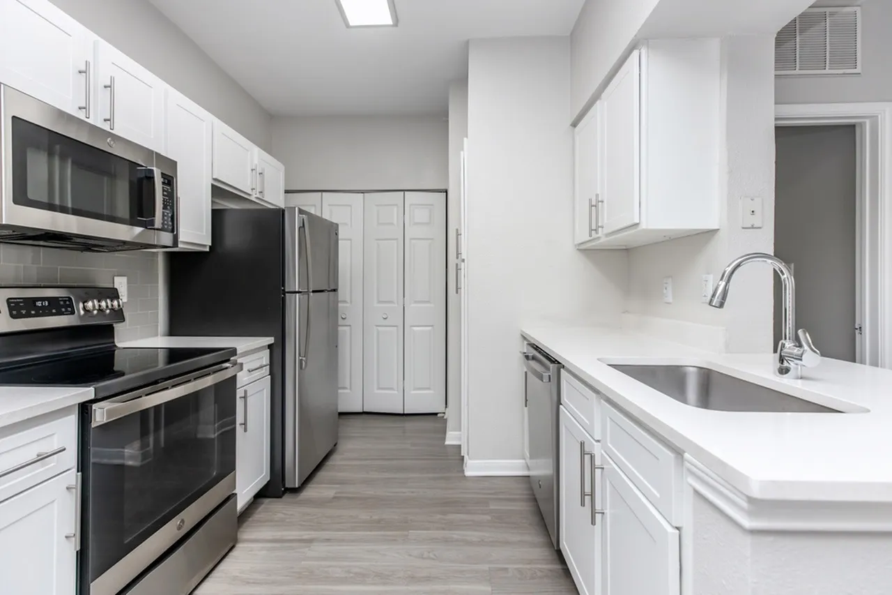 Kitchen, white shaker cabinetry, stainless steel appliances, quartz countertops, wood-style plank flooring
