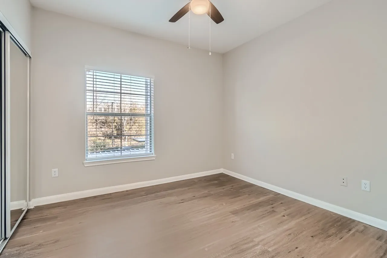 Bedroom, wood-style plank flooring, large window, ceiling fan, closet