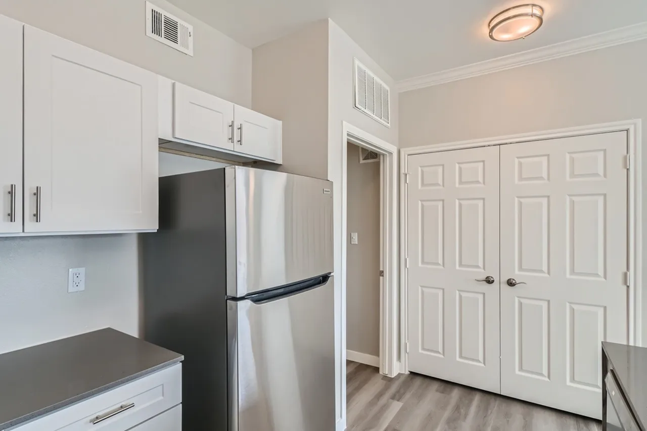 Kitchen with white shaker cabinetry, gray countertops, stainless appliances, wood-style plank flooring, double bedroom doors