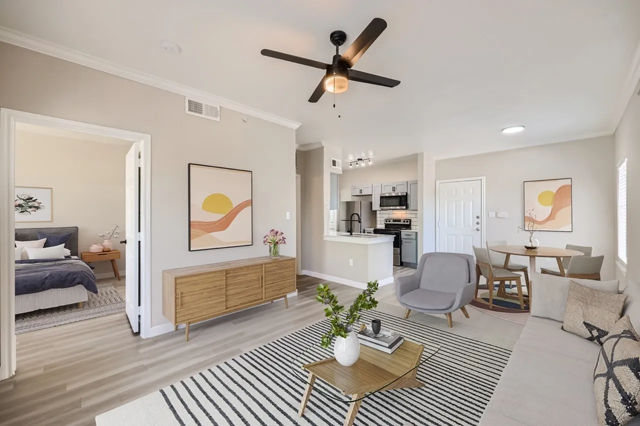 Living room with wood-style plank flooring, striped area rug, ceiling fan, contemporary artwork, gray armchair