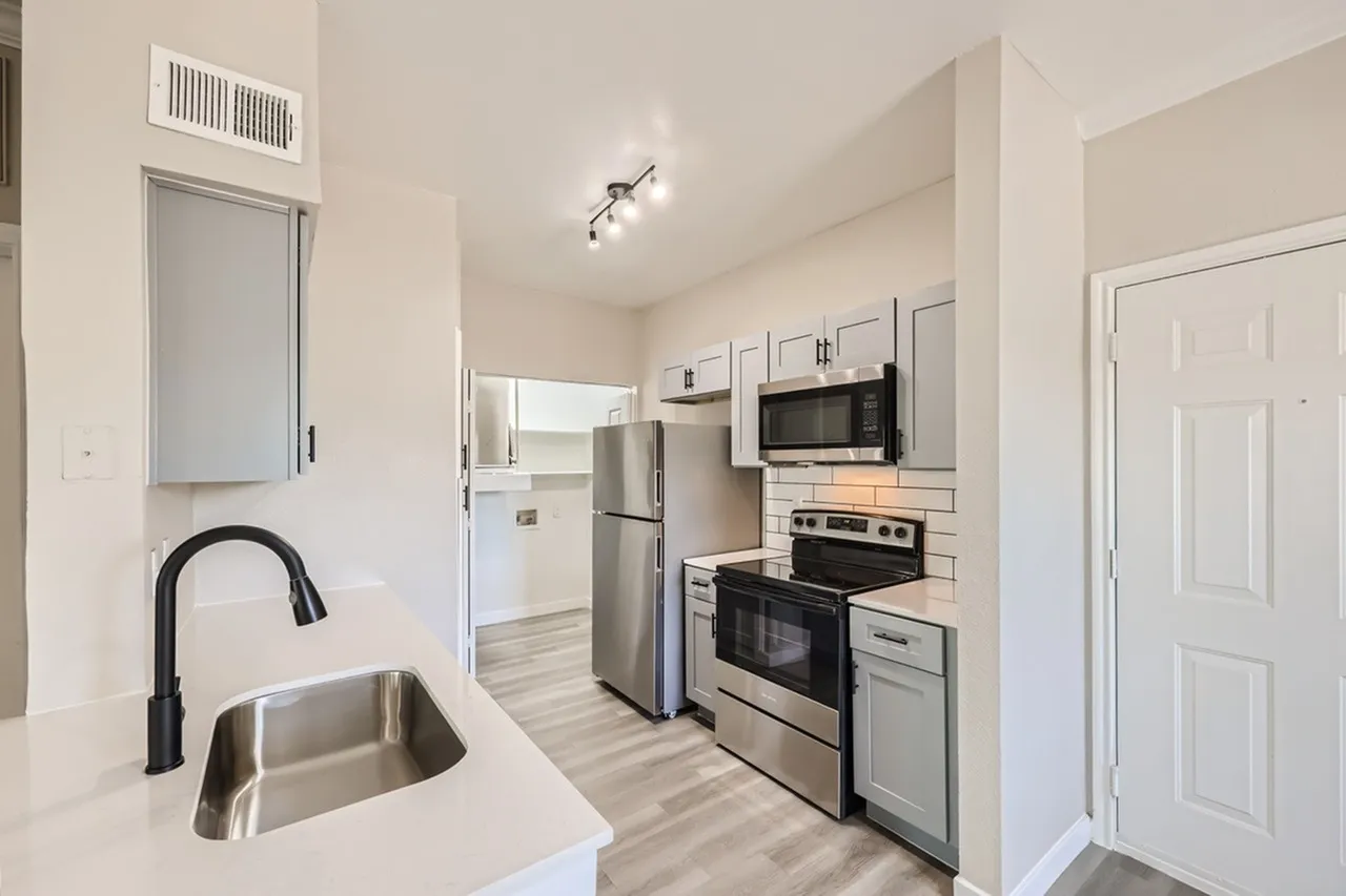 Kitchen, stainless steel appliances, white shaker cabinetry, quartz countertops, wood-style plank flooring