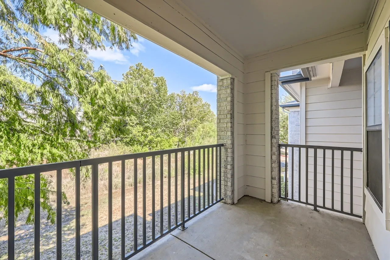 Covered balcony, black metal railing, concrete floor, tree views