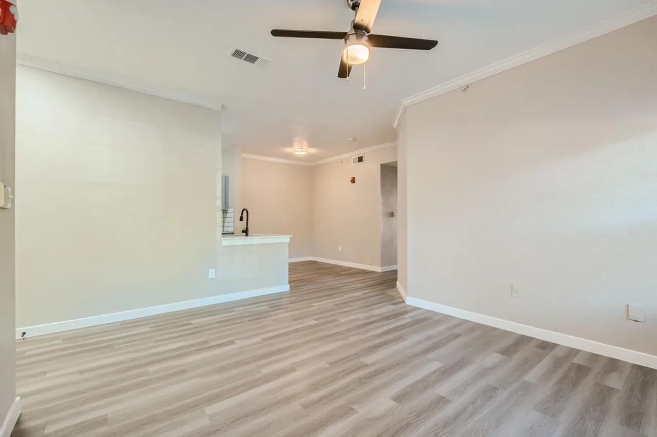 Open living area, wood-style plank flooring, white cabinetry, ceiling fan