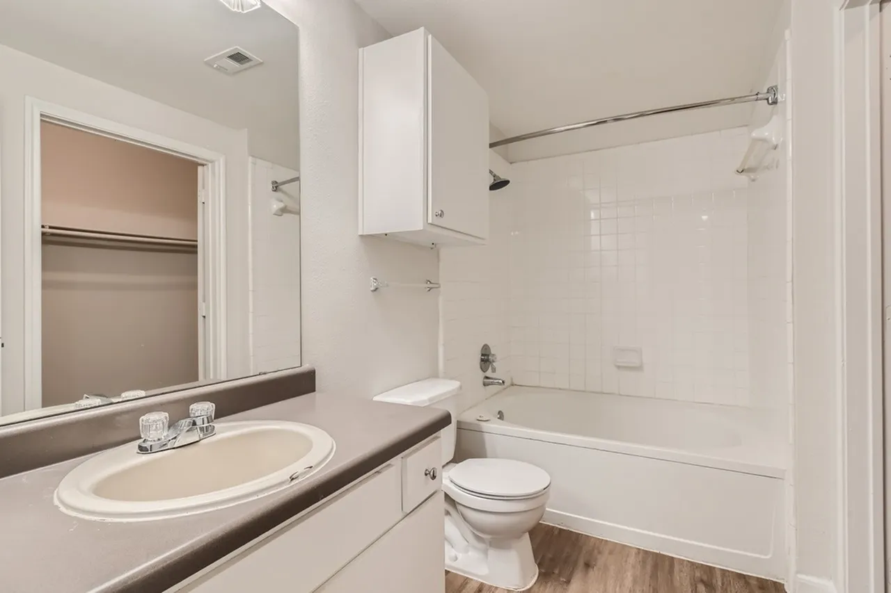 Primary bathroom, white cabinetry, dark countertop, round sink, mirror