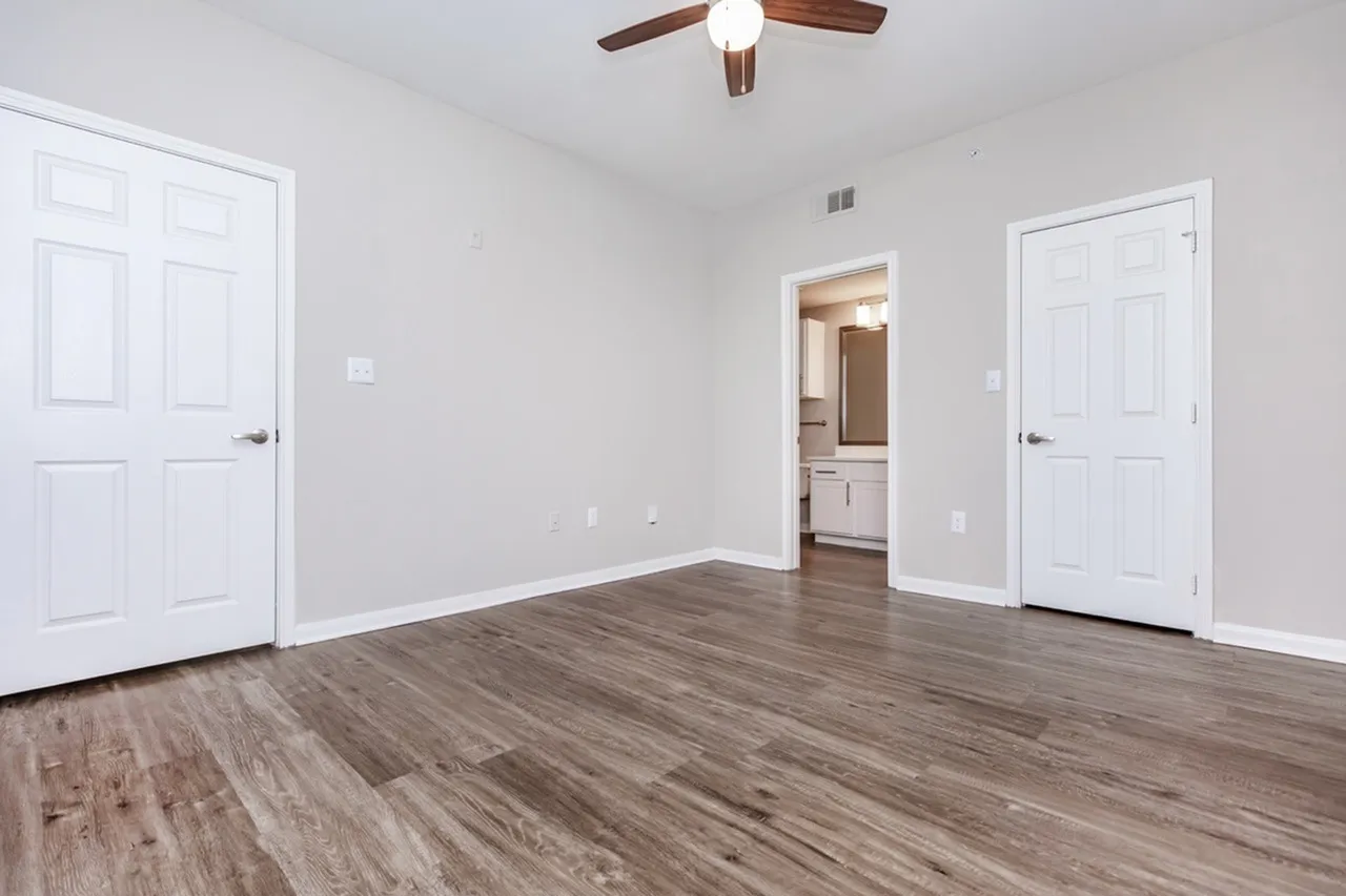 Primary bedroom, wood-style plank flooring, ceiling fan, multiple closets