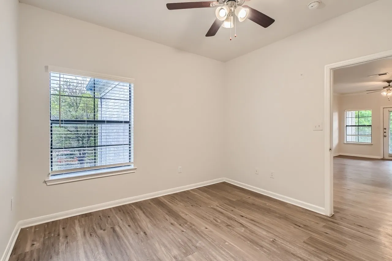 Bedroom, wood-style plank flooring, window with blinds, ceiling fan, open doorway