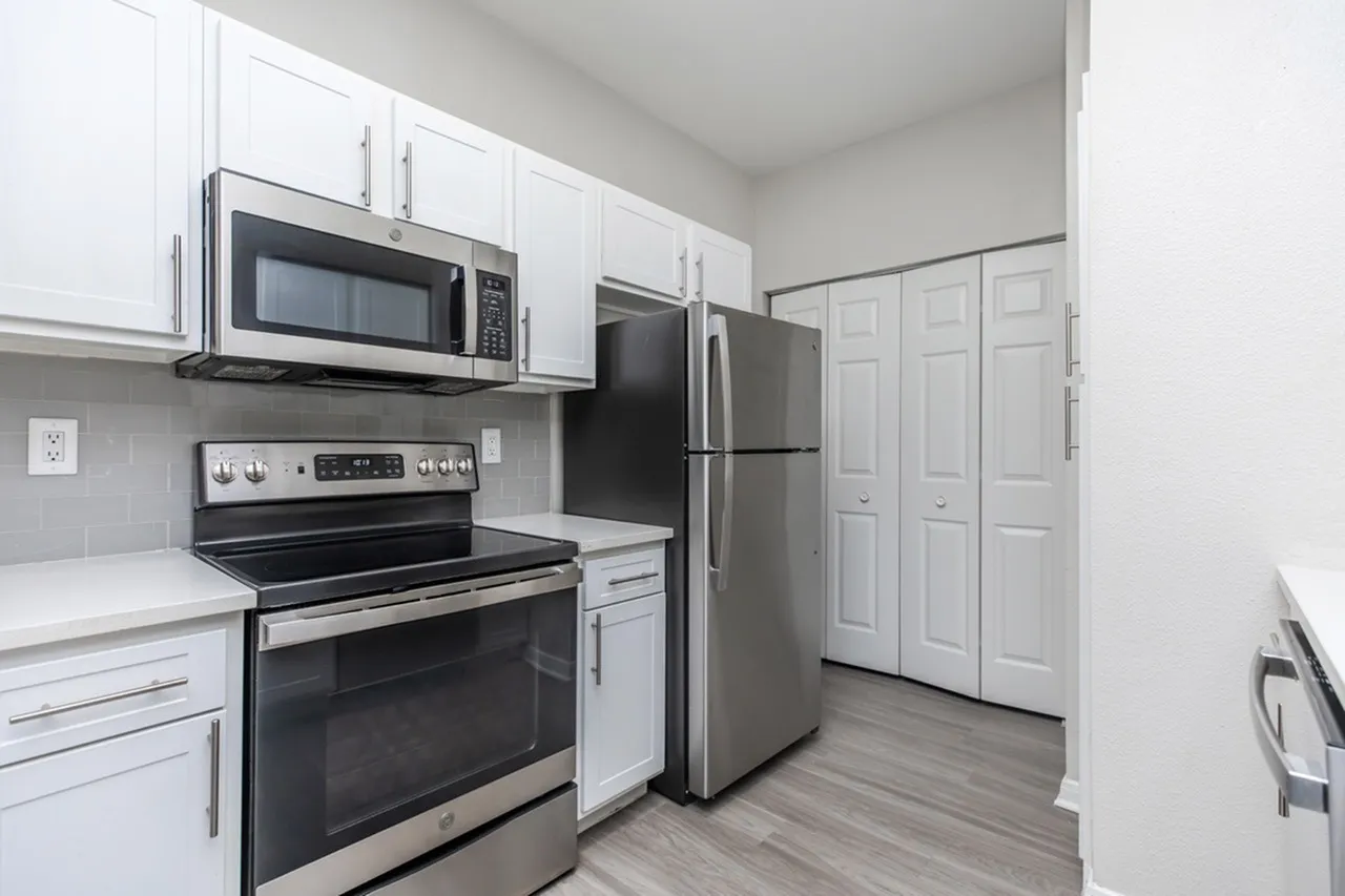 Kitchen, white shaker cabinetry, stainless steel appliances, wood-style plank flooring