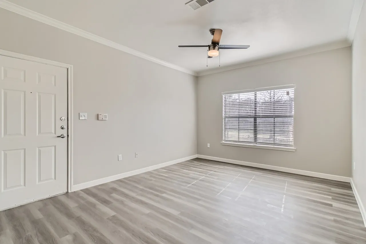 Bedroom, wood-style plank flooring, ceiling fan, large window with blinds, white entry door