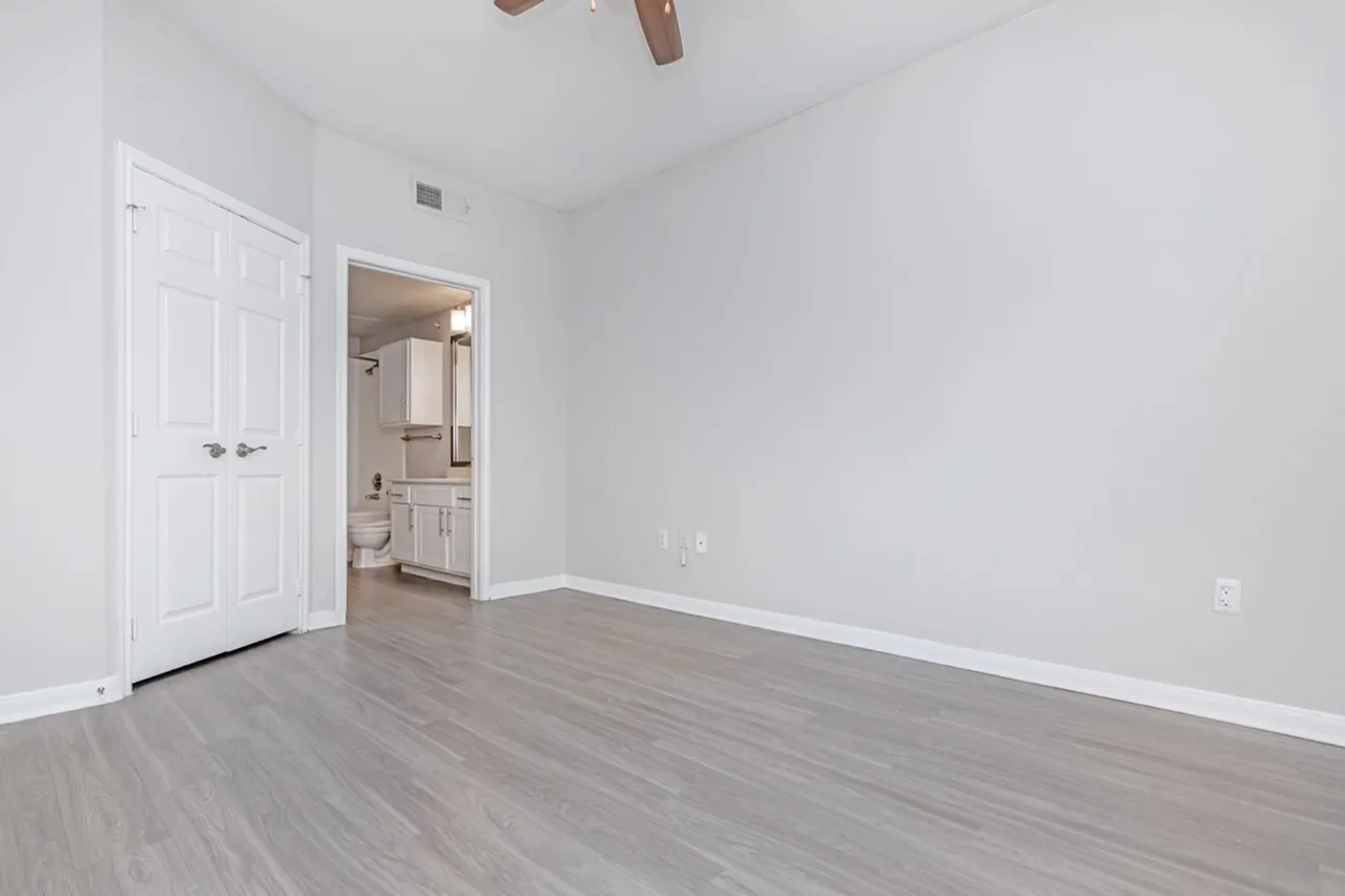 Primary bedroom, wood-style plank flooring, ceiling fan, ensuite bathroom entry