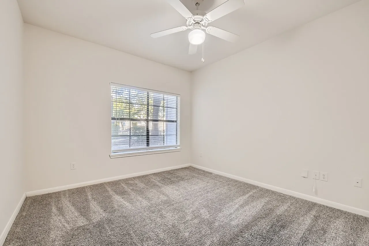 Bedroom, gray carpet flooring, ceiling fan with light, window with blinds