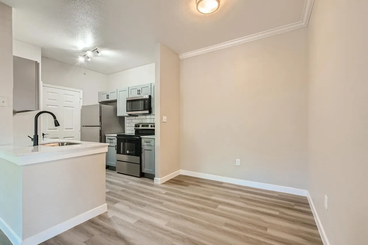 Kitchen with white cabinetry, stainless appliances, white countertops, wood-style plank flooring