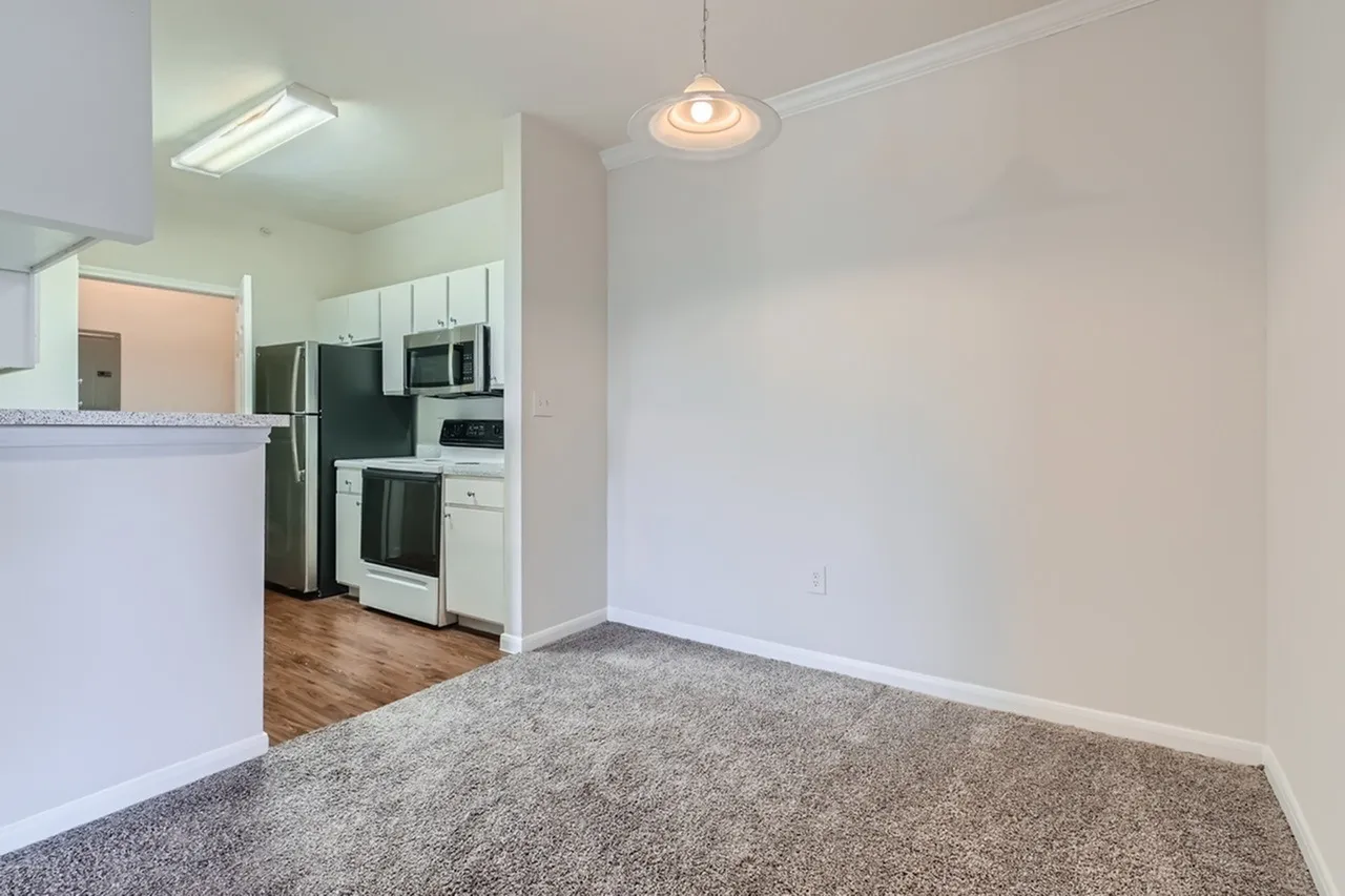 Dining area, gray carpet, wood-style plank flooring in kitchen, white cabinetry, stainless appliances
