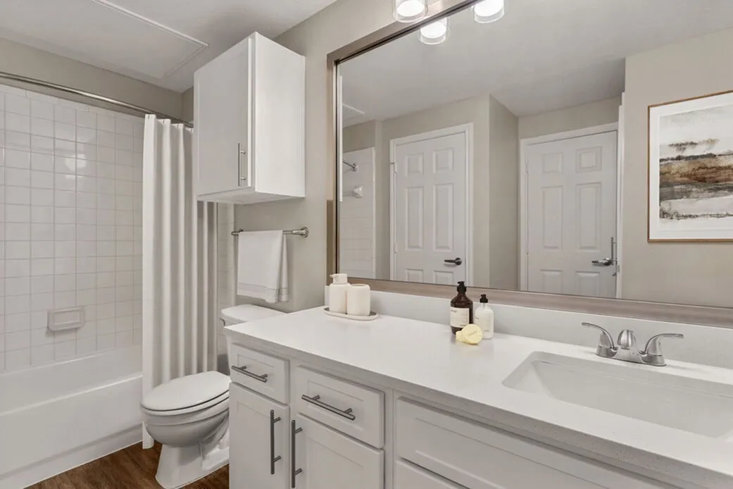 Primary bathroom, double vanity with white quartz countertops, gray cabinetry, large mirror, chrome fixtures
