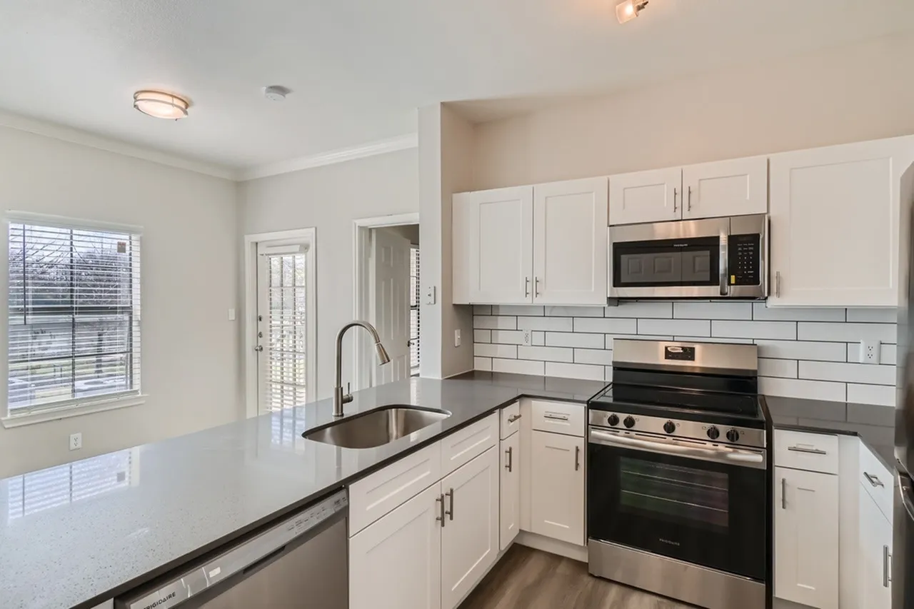 Kitchen, white shaker cabinetry, dark quartz countertops, stainless appliances, subway tile backsplash