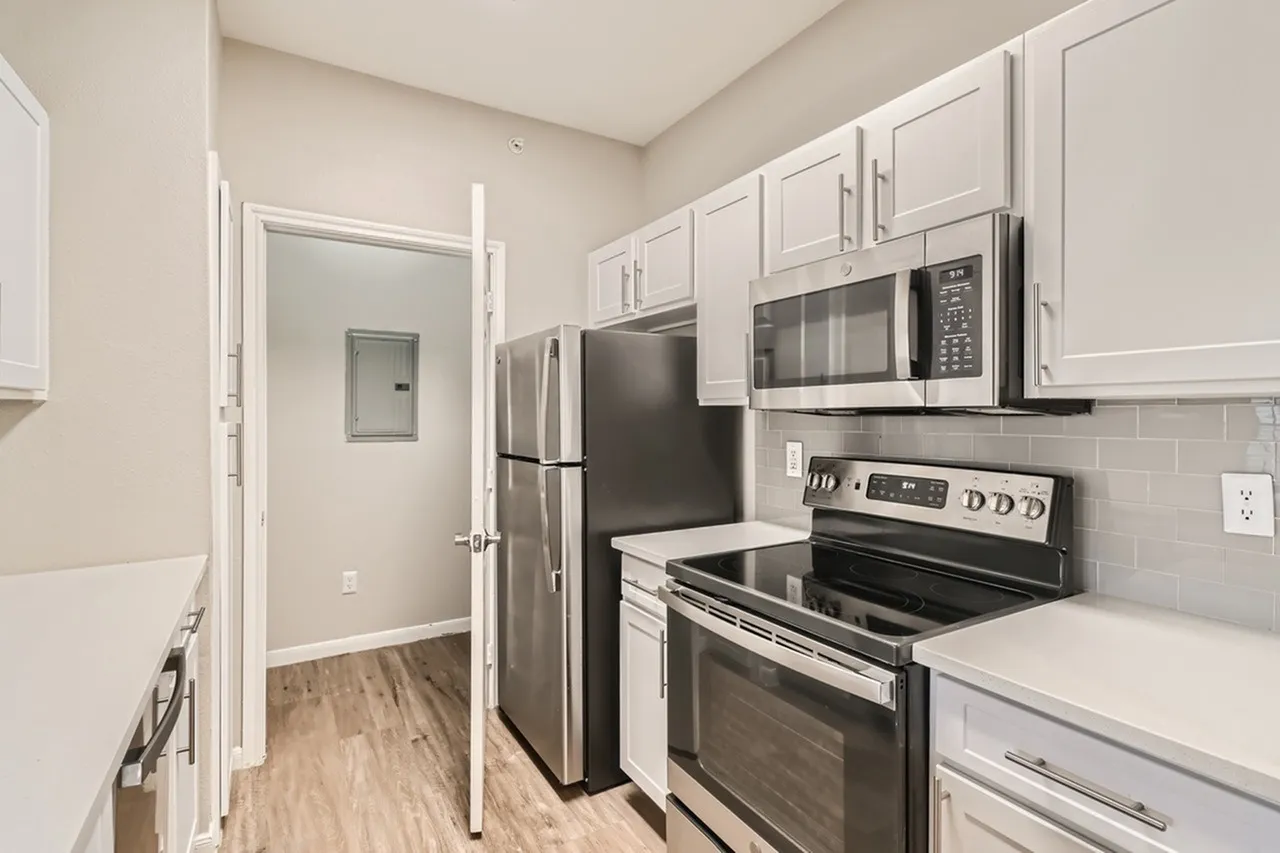Kitchen, white shaker cabinetry, quartz countertops, stainless steel appliances, wood-style plank flooring