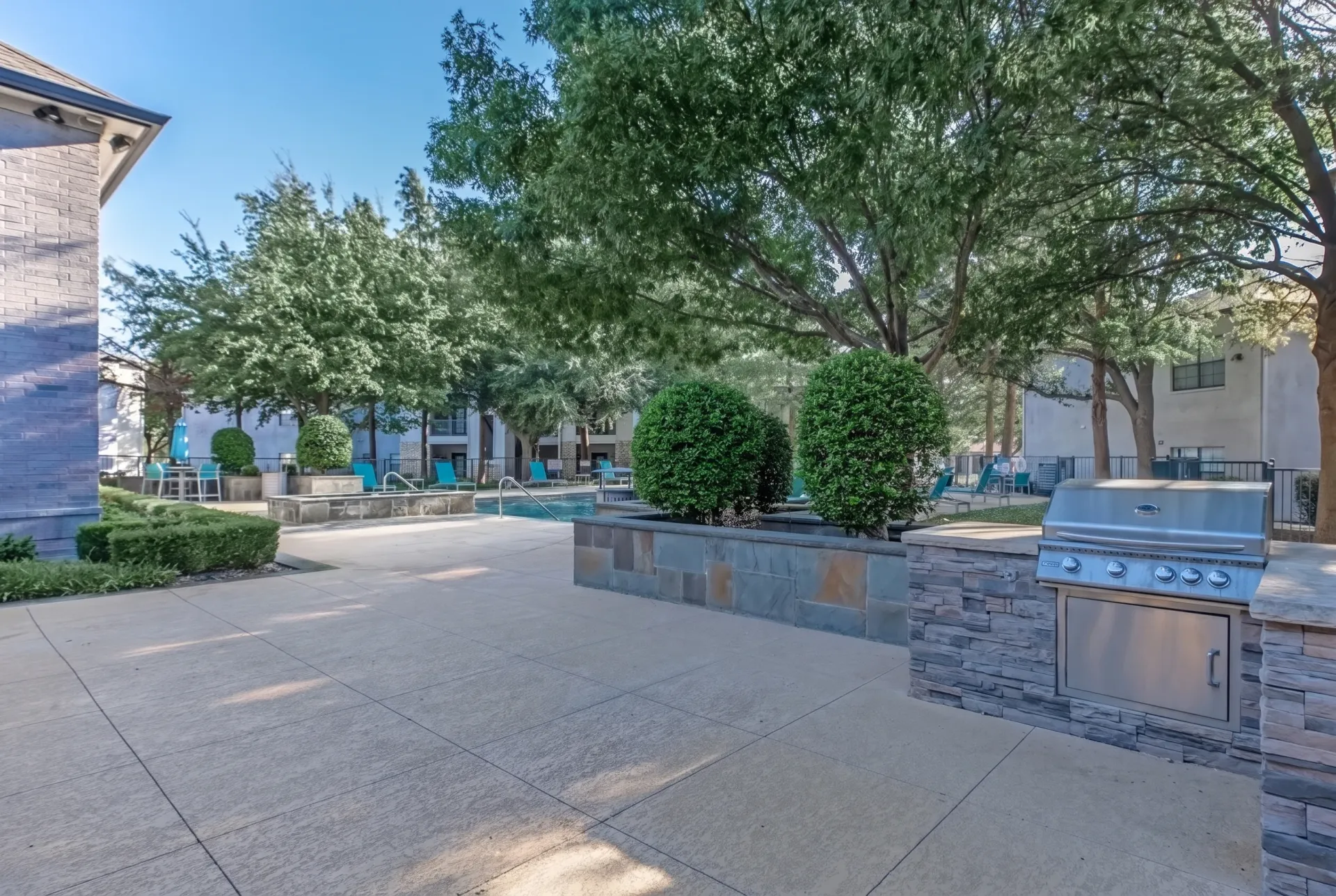 Outdoor patio, stainless steel grill, stone countertops, mature trees, lounging seating
