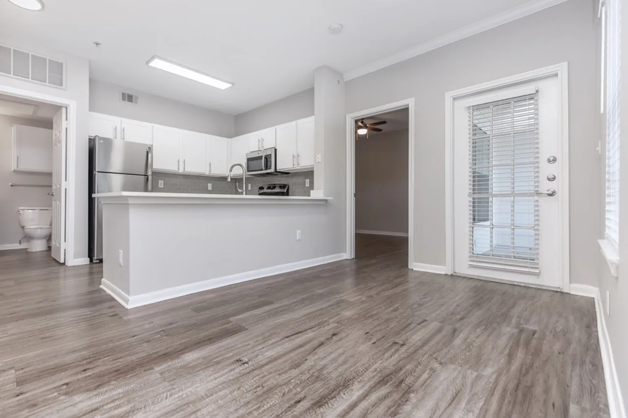 Kitchen, white shaker cabinetry, stainless appliances, wood-style plank flooring, island with seating