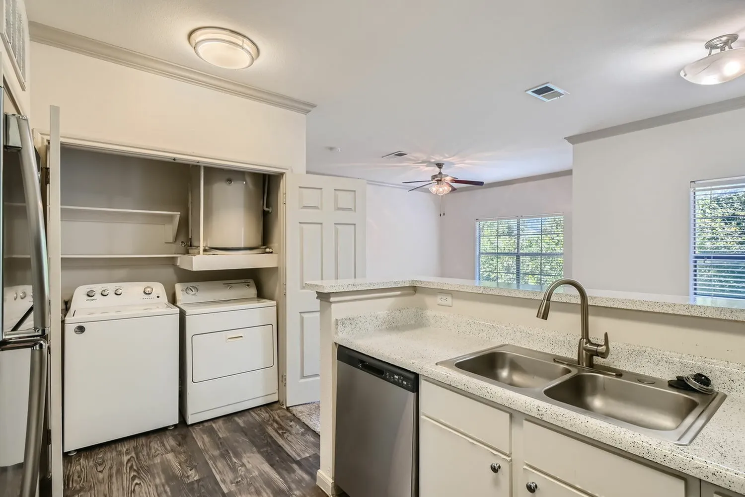 Kitchen, granite countertops, stainless steel double sink, white shaker cabinetry, wood-style plank flooring, white appliances, laundry closet with washer and dryer