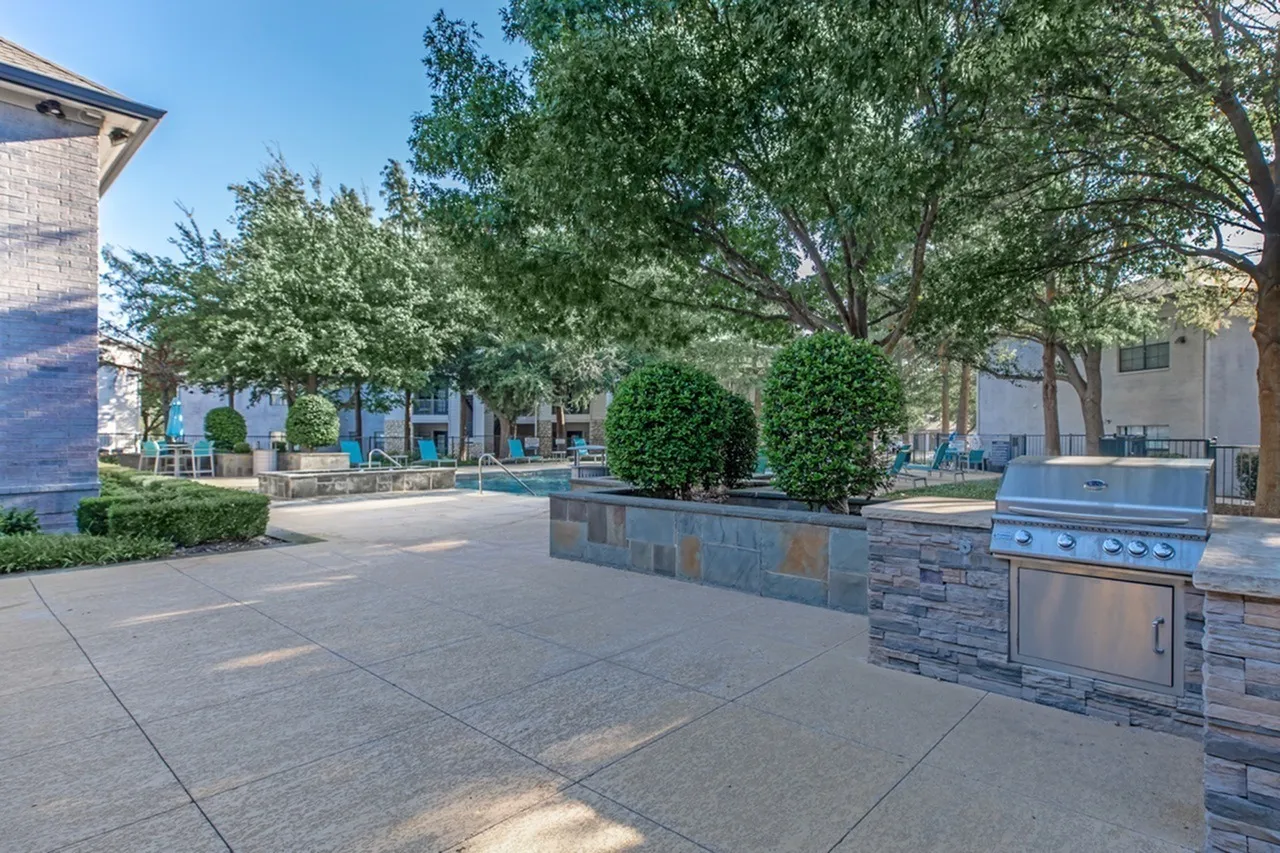 Outdoor patio, stainless steel grill, stone countertops, mature trees, lounging seating