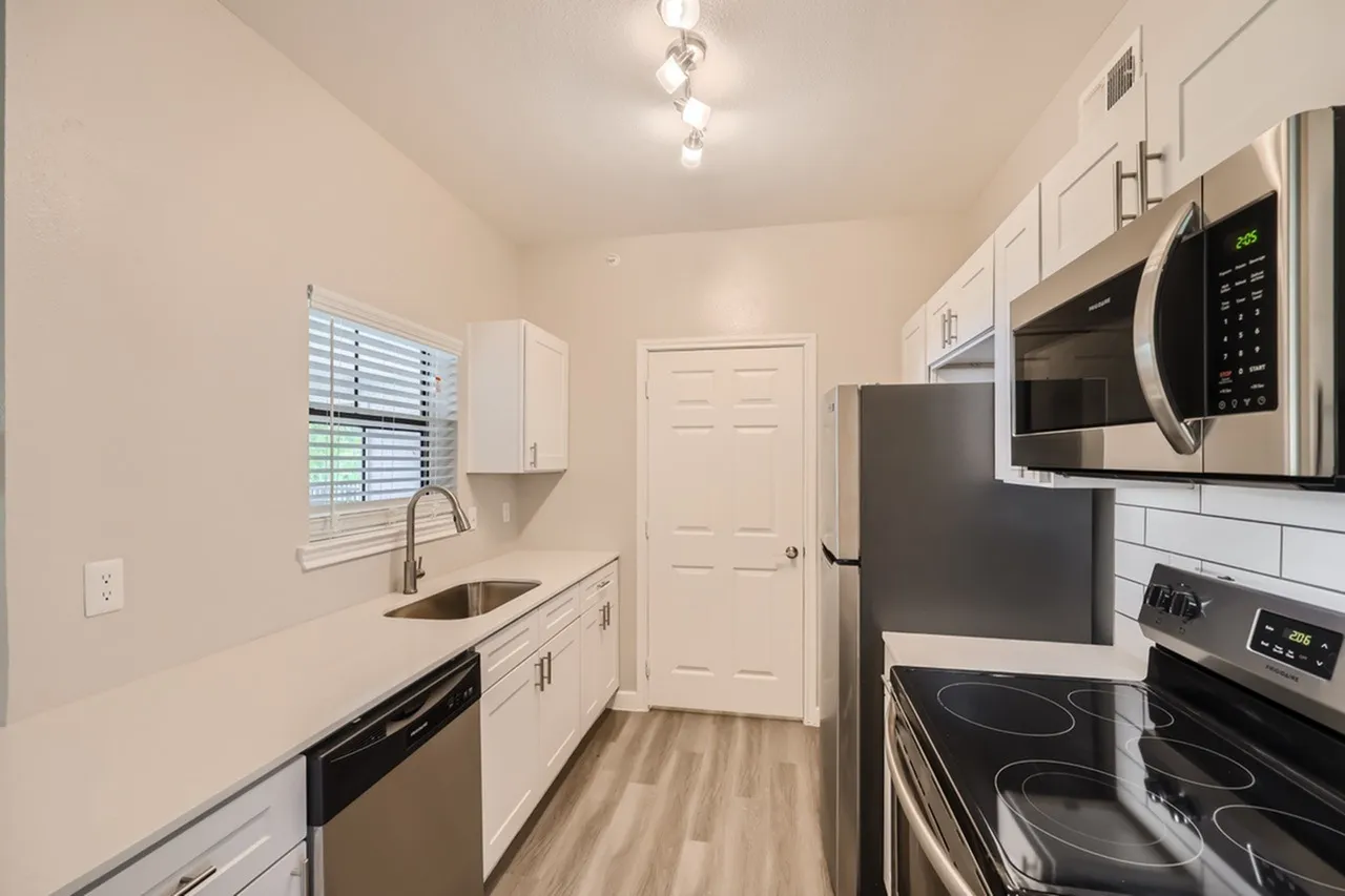 Kitchen, white shaker cabinetry, stainless steel appliances, wood-style plank flooring