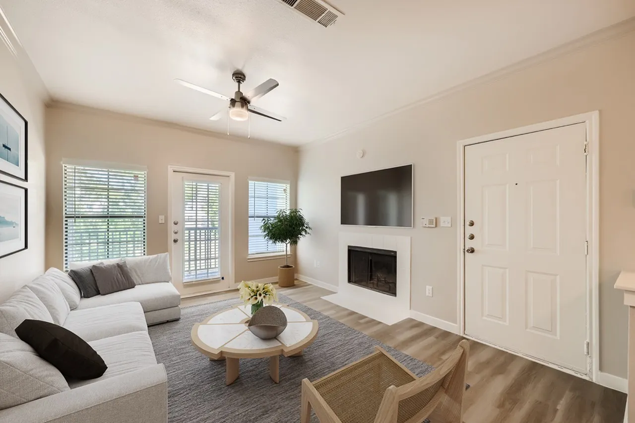 Living room with wood-style plank flooring, ceiling fan, fireplace, sectional sofa, round coffee table