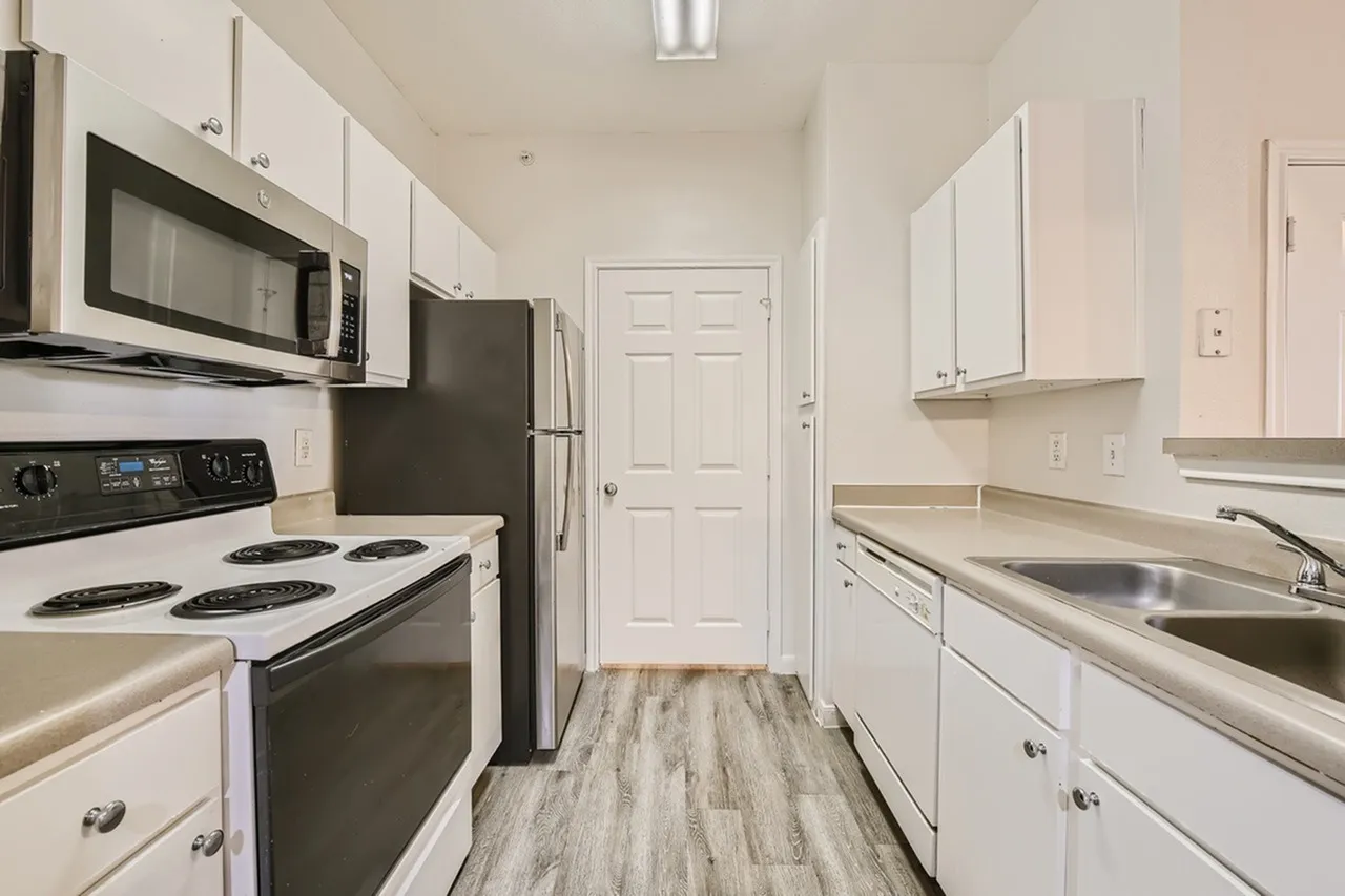 Kitchen, white cabinetry, stainless steel appliances, wood-style plank flooring, black range