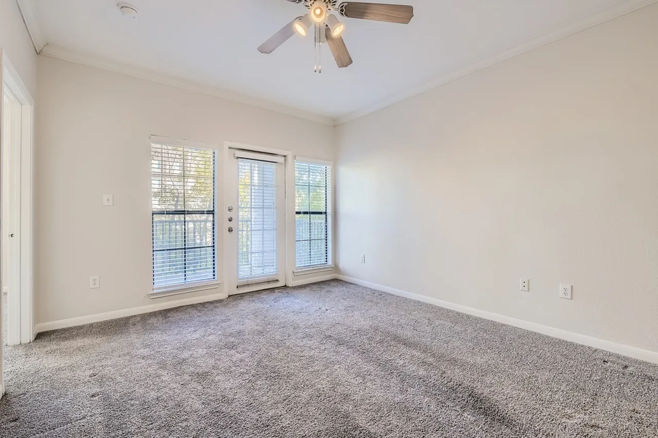 Bedroom, gray carpet flooring, ceiling fan, glass sliding doors with shutters
