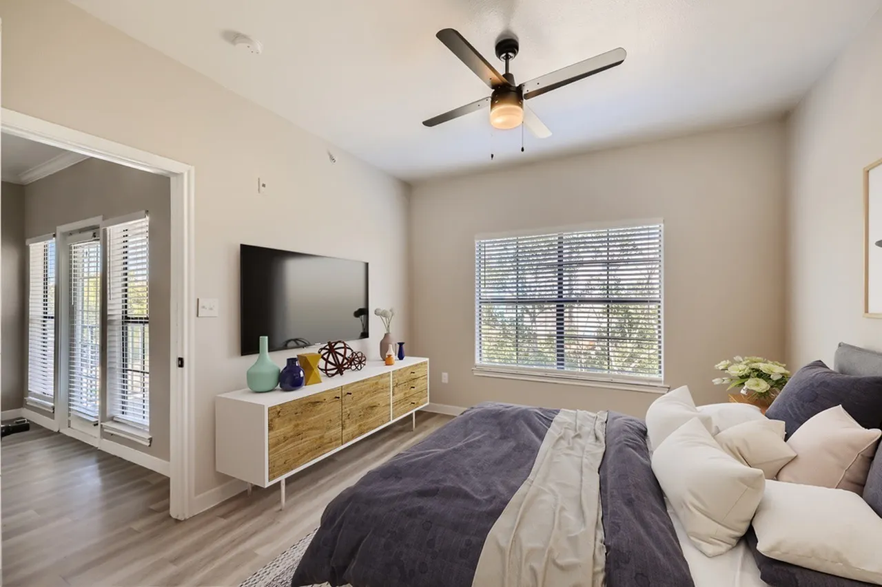 Primary bedroom, wood-style plank flooring, ceiling fan with light, TV on wooden dresser